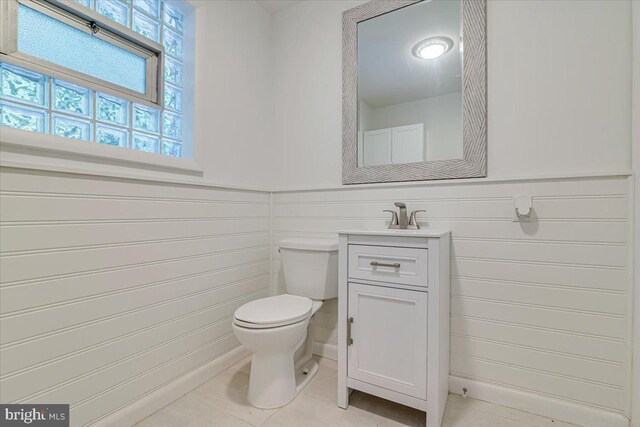 711 E Center St, Nesquehoning, PA 18240 - half bathroom with healthy amount of natural light, toilet, vanity, tile patterned floors, and a wainscoted wall