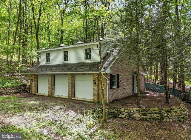 711 E Center St, Nesquehoning, PA 18240 - view of front of property with an attached garage, brick siding, and a forest view