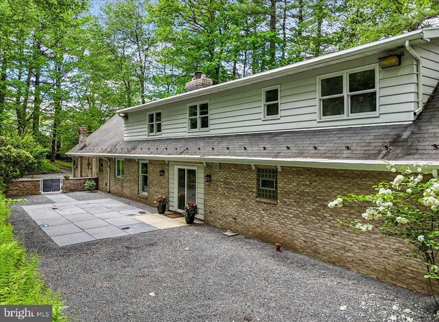 711 E Center St, Nesquehoning, PA 18240 - back of property featuring a chimney, a patio, and roof with shingles