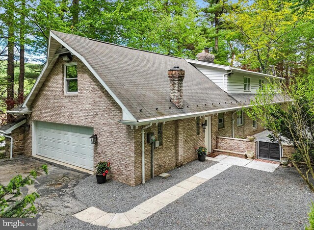 711 E Center St, Nesquehoning, PA 18240 - view of front facade with a chimney, a garage, a shingled roof, asphalt driveway, and a gate