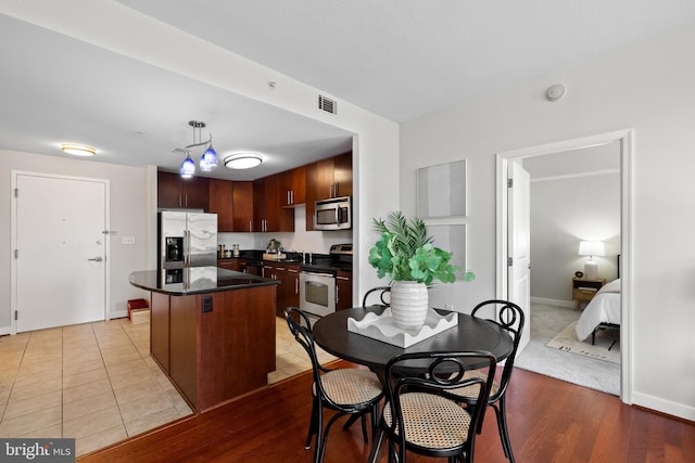157 Fleet St Unit 1006, Oxon Hill, MD 20745 - kitchen with appliances with stainless steel finishes, dark countertops, a kitchen island, decorative light fixtures, and light wood-style floors