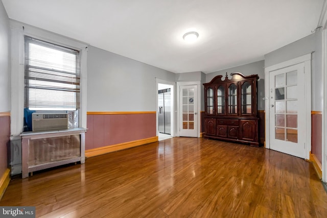 7252 Brent Rd, Upper Darby, PA 19082 - empty room featuring wood finished floors, wainscoting, french doors, cooling unit, and radiator heating unit