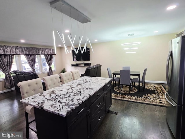 402 W Maple Ave, Sterling, VA 20164 - kitchen with freestanding refrigerator, dark cabinetry, a breakfast bar area, open floor plan, and dark wood-type flooring