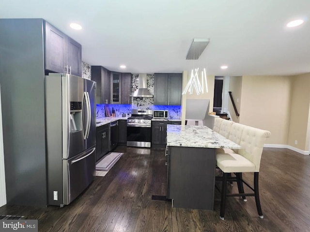 402 W Maple Ave, Sterling, VA 20164 - kitchen featuring appliances with stainless steel finishes, wall chimney exhaust hood, a breakfast bar, light stone counters, and recessed lighting