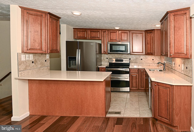 8110 Winter Blue Ct, Springfield, VA 22153 - kitchen featuring appliances with stainless steel finishes, a sink, a peninsula, light countertops, and tasteful backsplash