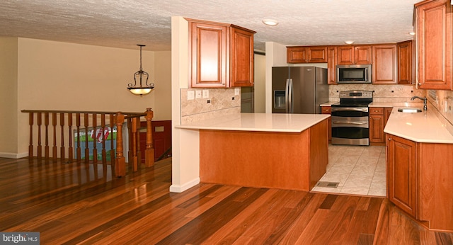 8110 Winter Blue Ct, Springfield, VA 22153 - kitchen featuring appliances with stainless steel finishes, a sink, a peninsula, backsplash, and a textured ceiling