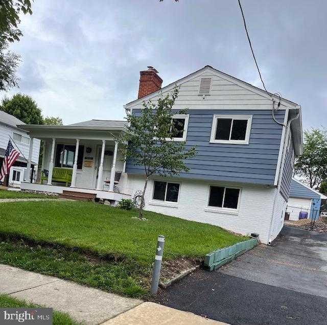 10713 Douglas Ave, Silver Spring, MD 20902 - tri-level home with a chimney, covered porch, a front lawn, driveway, and brick siding