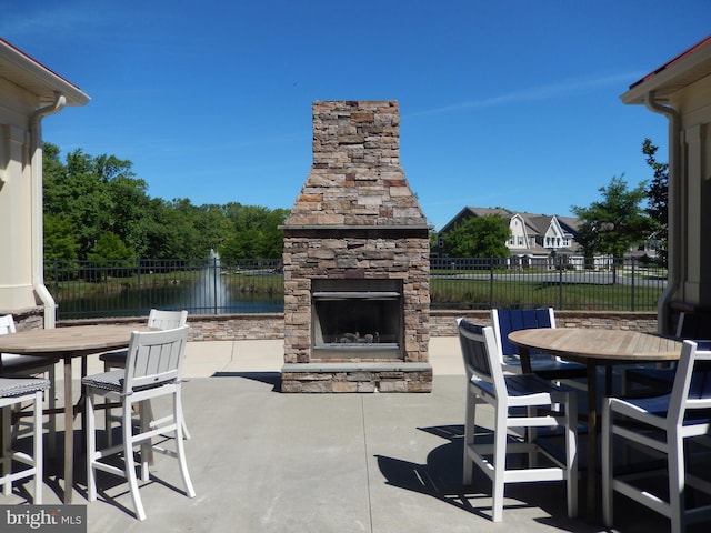20172 Trap Pond Ct, Millville, DE 19967 - view of patio featuring an outdoor stone fireplace, outdoor dining space, and a water view