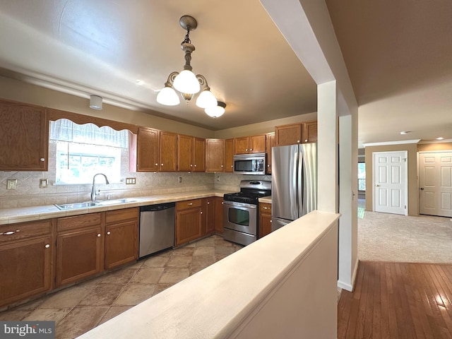 448 Country Club Dr, Lansdale, PA 19446 - kitchen featuring appliances with stainless steel finishes, a sink, a chandelier, brown cabinets, and crown molding