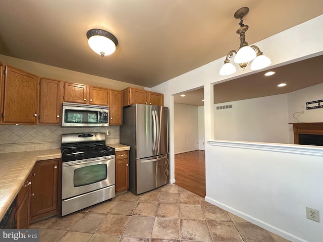 448 Country Club Dr, Lansdale, PA 19446 - kitchen featuring stainless steel appliances, decorative backsplash, tile counters, baseboards, and pendant lighting