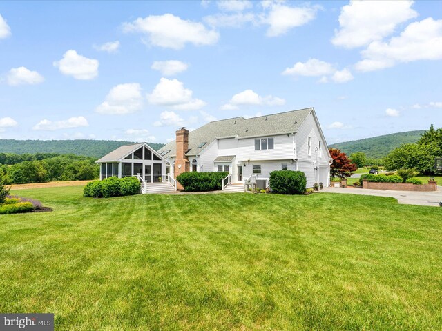 7100 Ewing Ct, Middletown, MD 21769 - back of house featuring a sunroom, driveway, a garage, a chimney, and a lawn