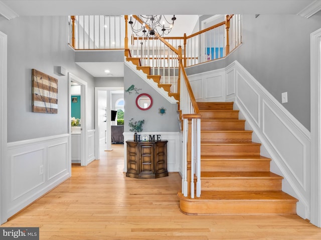 7100 Ewing Ct, Middletown, MD 21769 - staircase featuring a decorative wall, hardwood / wood-style flooring, a chandelier, wainscoting, and a towering ceiling