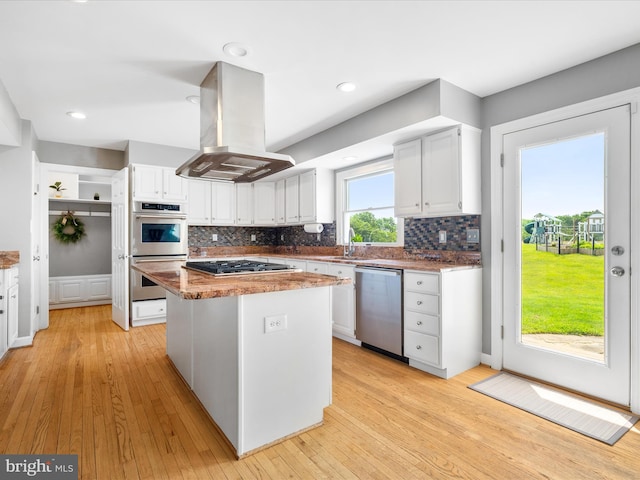 7100 Ewing Ct, Middletown, MD 21769 - kitchen with appliances with stainless steel finishes, island exhaust hood, white cabinetry, backsplash, and light wood finished floors