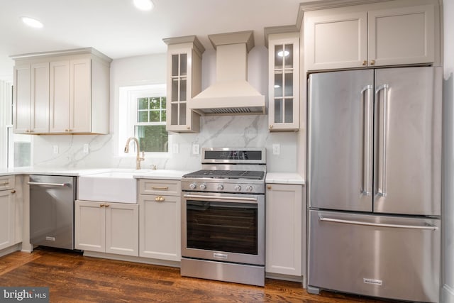 2304 W 19th St, Wilmington, DE 19806 - kitchen with appliances with stainless steel finishes, custom exhaust hood, decorative backsplash, dark wood-style flooring, and light countertops
