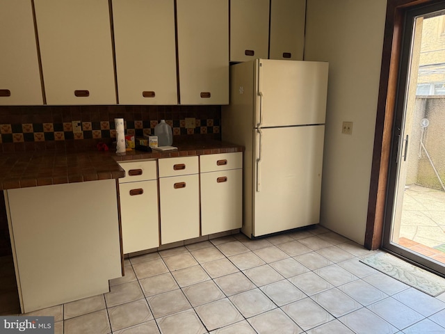 914 Fernon St, Philadelphia, PA 19148 - kitchen with freestanding refrigerator, tile counters, backsplash, and white cabinets