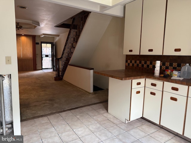 914 Fernon St, Philadelphia, PA 19148 - kitchen featuring light colored carpet, a ceiling fan, white cabinetry, tasteful backsplash, and tile counters