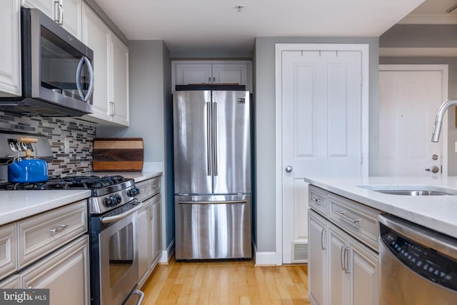 1201 N Garfield St Unit 604, Arlington, VA 22201 - kitchen featuring appliances with stainless steel finishes, a sink, light wood-style floors, tasteful backsplash, and baseboards