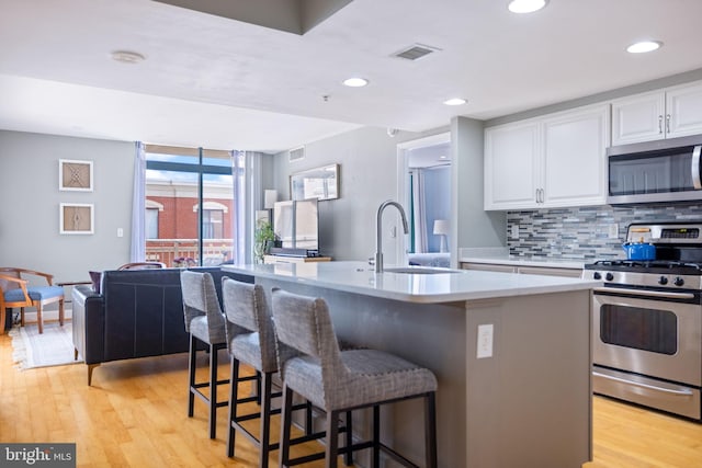 1201 N Garfield St Unit 604, Arlington, VA 22201 - kitchen with stainless steel appliances, tasteful backsplash, white cabinetry, a sink, and light wood-style floors