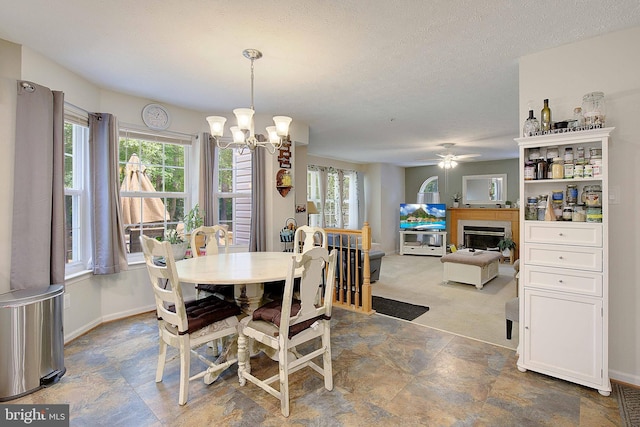 600 Small Reward Rd, Huntingtown, MD 20639 - dining area featuring a fireplace, a chandelier, stone finish floors, baseboards, and a textured ceiling