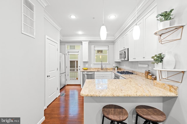 331 K St SE, Washington, DC 20003 - kitchen featuring appliances with stainless steel finishes, crown molding, a peninsula, white cabinetry, and a kitchen bar