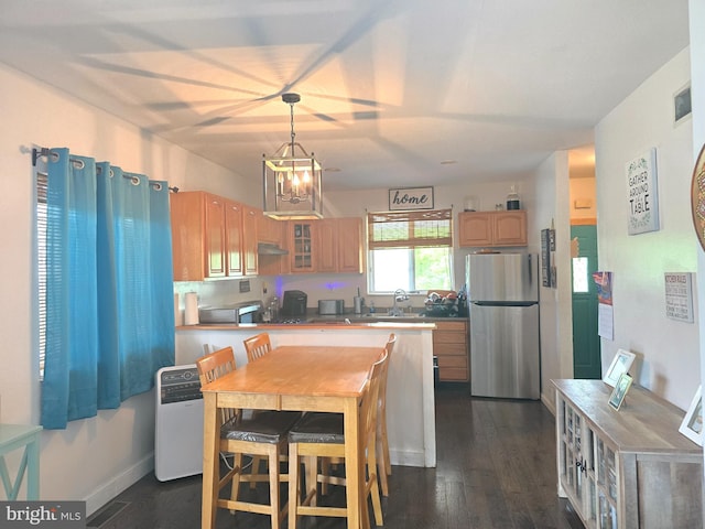 300 N Orchard Rd, Vineland, NJ 08360 - kitchen featuring freestanding refrigerator, under cabinet range hood, dark wood-style flooring, glass insert cabinets, and decorative light fixtures