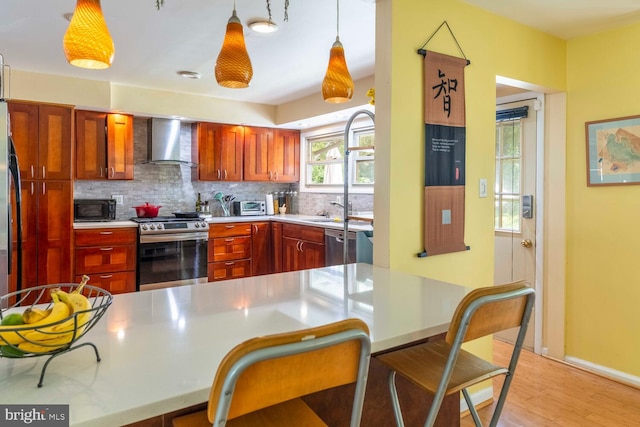 1030 Rock Creek Dr, Wyncote, PA 19095 - kitchen featuring appliances with stainless steel finishes, wall chimney exhaust hood, tasteful backsplash, light countertops, and light wood-type flooring