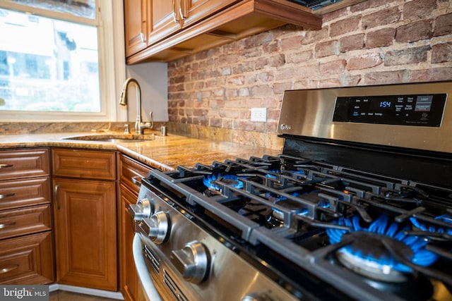 846 W 34th St W, Baltimore, MD 21211 - kitchen featuring gas range, a sink, brown cabinets, tasteful backsplash, and light stone counters