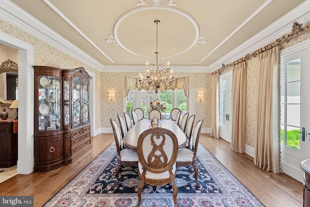 22701 Creighton Farms Dr, Leesburg, VA 20175 - dining area featuring a chandelier, wallpapered walls, light wood-style floors, a raised ceiling, and crown molding