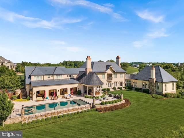 22701 Creighton Farms Dr, Leesburg, VA 20175 - rear view of property featuring a lawn, a patio, a pool with connected hot tub, a chimney, and a standing seam roof