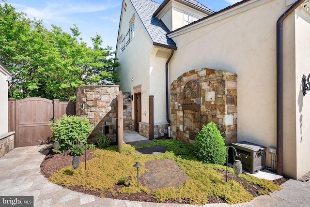 22701 Creighton Farms Dr, Leesburg, VA 20175 - doorway to property featuring a gate, stucco siding, a high end roof, and stone siding