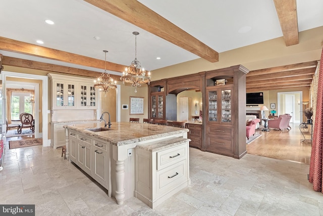 22701 Creighton Farms Dr, Leesburg, VA 20175 - kitchen with a sink, beamed ceiling, arched walkways, an island with sink, and glass insert cabinets
