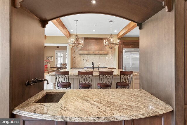 22701 Creighton Farms Dr, Leesburg, VA 20175 - kitchen featuring a center island with sink, stainless steel built in refrigerator, arched walkways, a sink, and beamed ceiling