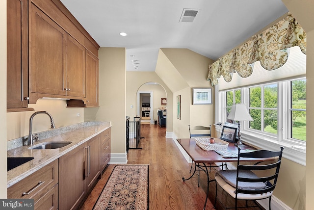 22701 Creighton Farms Dr, Leesburg, VA 20175 - kitchen featuring a sink, arched walkways, wood finished floors, baseboards, and lofted ceiling