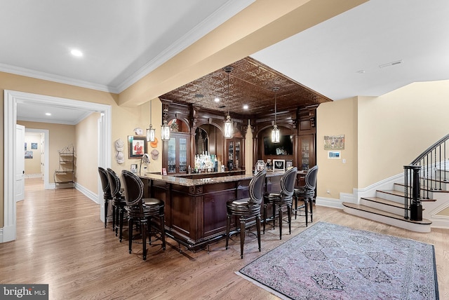 22701 Creighton Farms Dr, Leesburg, VA 20175 - indoor bar featuring light wood-style floors, stairway, baseboards, ornamental molding, and pendant lighting