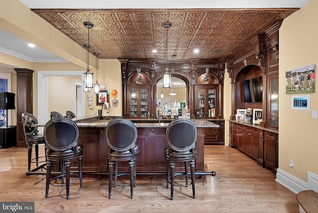 22701 Creighton Farms Dr, Leesburg, VA 20175 - indoor wet bar featuring light wood finished floors, an ornate ceiling, ornamental molding, decorative light fixtures, and baseboards