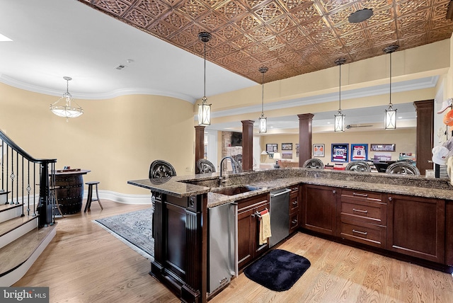 22701 Creighton Farms Dr, Leesburg, VA 20175 - kitchen featuring ornate columns, stainless steel dishwasher, light wood-style flooring, a sink, and pendant lighting