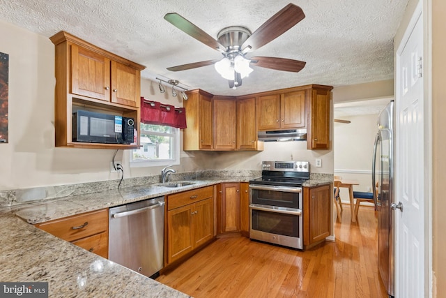 8017 Cipher Row, Jessup, MD 20794 - kitchen featuring stainless steel appliances, under cabinet range hood, brown cabinetry, and a textured ceiling