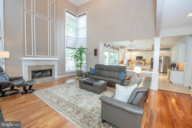 32 Eagleton Farm Rd, Newtown, PA 18940 - living room featuring a high ceiling, light wood-style flooring, decorative columns, and a fireplace with flush hearth