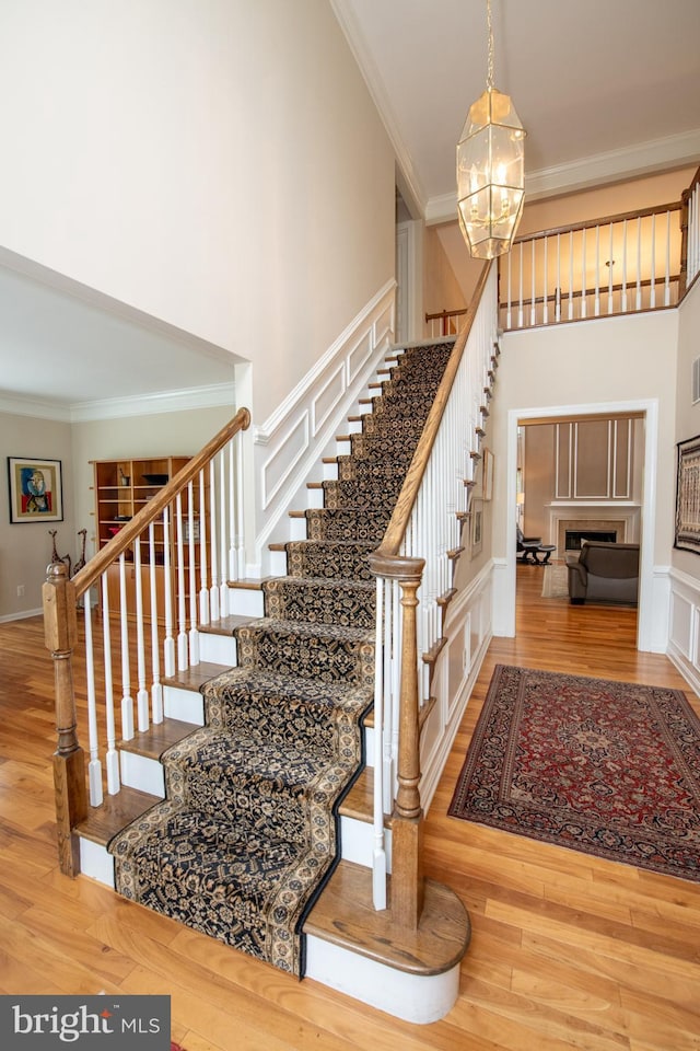 32 Eagleton Farm Rd, Newtown, PA 18940 - staircase featuring ornamental molding, a chandelier, wood finished floors, a fireplace, and a high ceiling