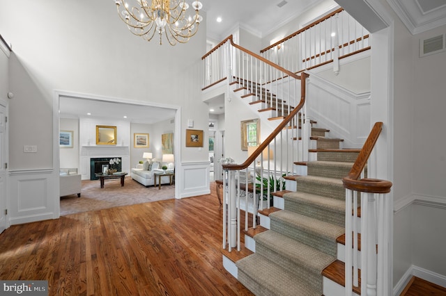 704 Turnbridge Rd, Wayne, PA 19087 - stairway featuring a decorative wall, wood finished floors, a glass covered fireplace, a high ceiling, and a chandelier