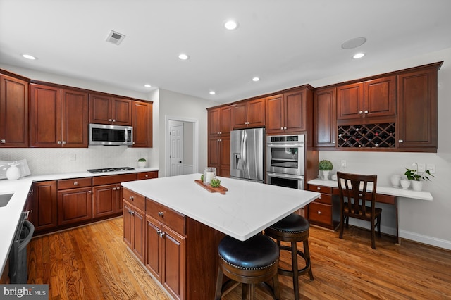 704 Turnbridge Rd, Wayne, PA 19087 - kitchen with appliances with stainless steel finishes, a kitchen island, wood finished floors, backsplash, and recessed lighting