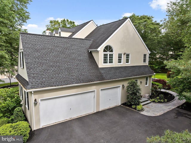 704 Turnbridge Rd, Wayne, PA 19087 - view of home's exterior with roof with shingles, asphalt driveway, stucco siding, a chimney, and a garage