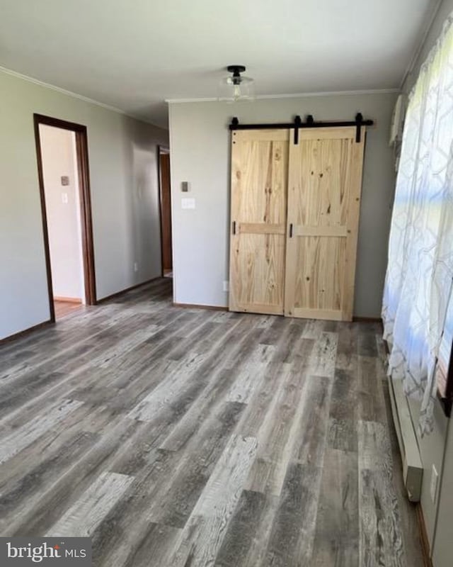 230 Eisenhower Dr, Orwigsburg, PA 17961 - unfurnished bedroom with a barn door, wood finished floors, crown molding, and baseboards