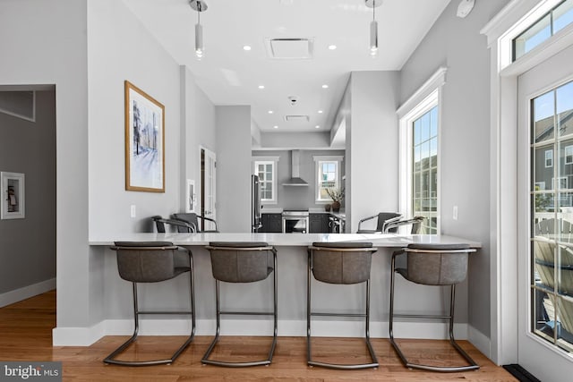 18010 Woods Overlook Dr, Dumfries, VA 22026 - kitchen with wall chimney range hood, stainless steel appliances, wood finished floors, pendant lighting, and recessed lighting