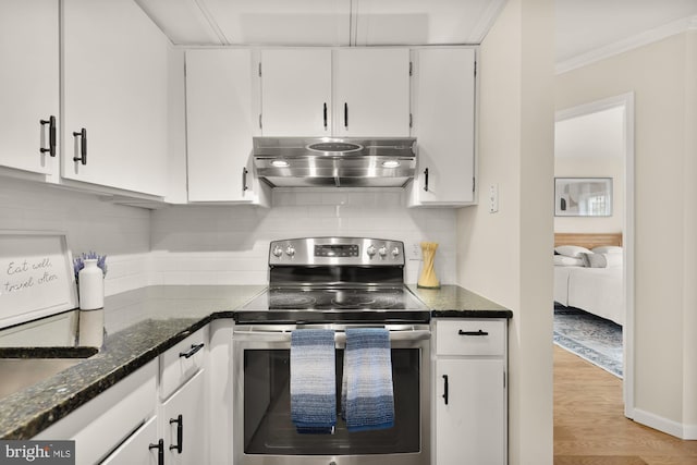 1801 Park Rd NW Unit 2, Washington, DC 20010 - kitchen with stainless steel electric stove, wall chimney exhaust hood, white cabinetry, dark stone countertops, and light wood finished floors