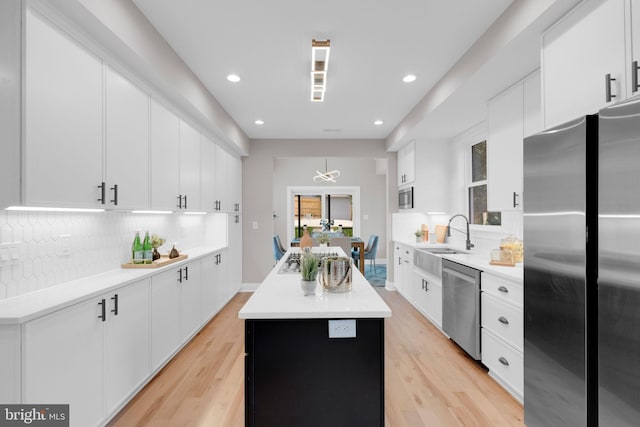 1427 Jackson St NE, Washington, DC 20017 - kitchen with appliances with stainless steel finishes, a sink, a center island, backsplash, and light wood-style floors