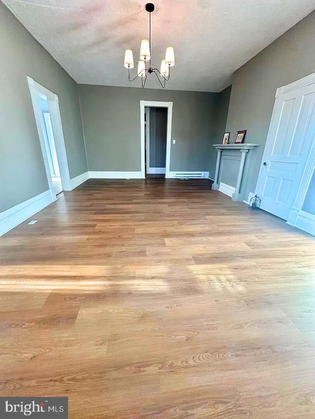 933 Mccormick Blvd, Clifton Forge, VA 24422 - unfurnished dining area with a chandelier, wood finished floors, baseboards, a textured ceiling, and a baseboard radiator