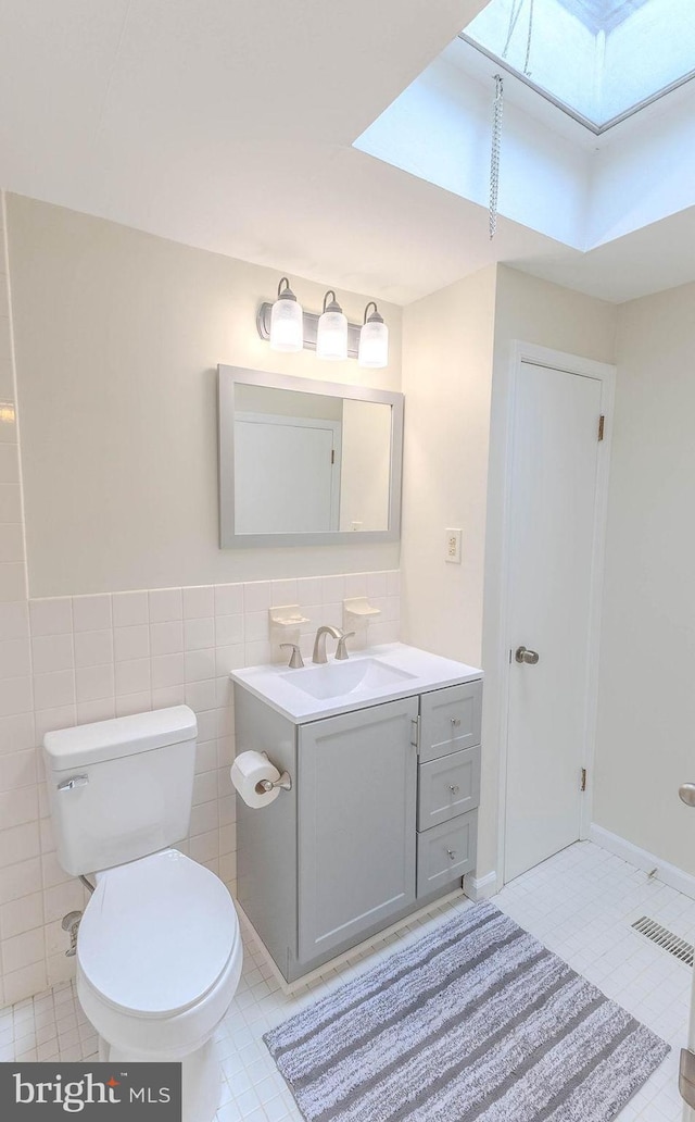 4128 Whiting Rd, Philadelphia, PA 19154 - bathroom featuring a skylight, vanity, toilet, tile patterned floors, and tile walls
