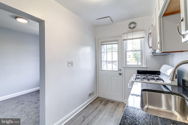 151 Bennett Rd, Essex, MD 21221 - kitchen featuring a sink, stainless steel microwave, dark stone countertops, baseboards, and light wood finished floors