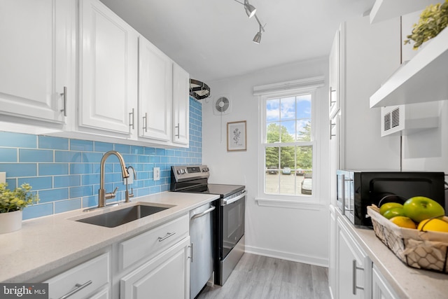 117 E Glebe Rd Unit C, Alexandria, VA 22305 - kitchen featuring a sink, stainless steel appliances, backsplash, light wood-style flooring, and white cabinets